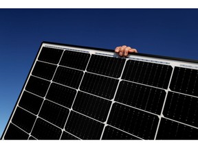 A Solarpro employee holds a LG Electronics Inc. NeON R 370W solar panel ahead of installation on the rooftop of a residential property in Sydney, Australia, on Monday, May 17, 2021. Australia is the global leader in generating electricity from the sun. Some 27% of buildings had a solar system on their roof at the end of 2020, the highest proportion in the world, according to figures from BNEF.
