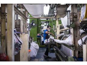 A factory employee handles fabric made from recycled plastic bottles at a Thai Taffeta Co. factory in Rayong, Thailand, on Friday, Oct. 22, 2021. A decline in active cases and increase in vaccinations over the past several weeks has allowed the government to gradually relax restrictions for businesses to reopen and travel to resume, which are part of its "living with Covid" strategy that recognizes the endemic nature of the virus. Photographer: Andre Malerba/Bloomberg
