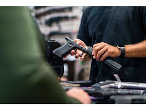 An employee shows a customer a Glock 17 pistol for sale at Redstone Firearms, in Burbank, California, US, on Friday, Sept. 16, 2022. While White men still represent the largest group of gun owners in the US, women, and specifically Black women, represent a growing share of the market. Photographer: Kyle Grillot/Bloomberg