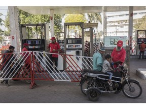 A worker refuels a motorcycle at a gas station in Karachi on Feb. 7. Photographer: Asim Hafeez/Bloomberg