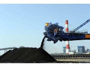 Workers use heavy machinery to sift through coal at the Adani Power company thermal power plant at Mundra.