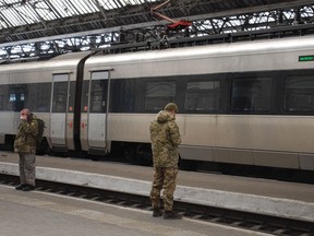 Passengers and military personnel wait on the platform of the Lviv train station in Western Ukraine on Feb. 18, 2023. Ukraine is appealing to Canada for rail parts and expertise to keep the embattled passenger and cargo rail system running as landmines and missile strikes threaten to stall the country's lifeline.