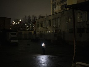 A woman uses her phone to light her way in Kyiv, Ukraine, Tuesday, Jan. 31, 2023.