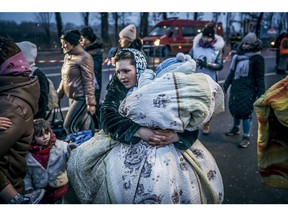 March 2, 2022. A Ukrainian woman carries a child in a blanket after crossing the border in Siret, Romania. Photographer: Andrei Pungovsch/Bloomberg