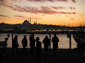 Commuters arrive at the Karakoy ferry terminal as the sun sets behind Suleymaniye mosque, background, in Istanbul, Turkey, Wednesday, Feb. 22, 2023.