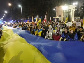 Participants carry a giant Ukrainian flag to mark the one year anniversary of the Russian invasion of Ukraine, in front of the Russian Embassy in Warsaw, Poland, Friday, Feb. 24, 2023.