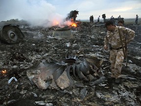 FILE - People walk amongst the debris at the crash site of a passenger plane near the village of Grabovo, Ukraine, July 17, 2014. An international team is presenting an update Wednesday Feb. 8, 2023 on its investigation into the 2014 downing of Malaysia Airlines flight MH17 over eastern Ukraine. The announcement comes nearly three months after a Dutch court convicted two Russians and a Ukrainian rebel for their roles in shooting down the Boeing 777 and killing all 298 people on board on July 17, 2014.