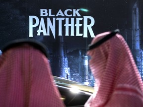FILE - Visitors wait in front of a "Black Panther" movie banner, during an invitation-only screening, at the King Abdullah Financial District Theater, in Riyadh, Saudi Arabia, on April 18, 2018. AMC Entertainment Holdings, the world's biggest cinema chain, has decided to exit Saudi Arabia's fast-growing market in the face of intense competition. The decision, announced Monday, Jan. 30, 2023, comes less than five years after AMC opened the kingdom's first movie theater following a decades-long ban.
