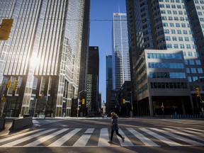 A woman crosses the street during morning commuting hours in the Financial District of Toronto.