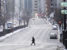 A woman wearing a face mask crosses Rene-Levesque boulevard in Montreal as the COVID-19 pandemic continues in Canada and around the world in 2021.