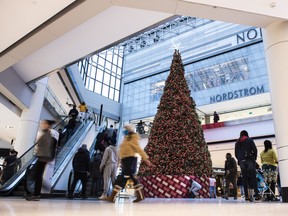 People pass a large Christmas tree as they go shopping on Christmas Eve at a mall in Ottawa.