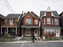 A cyclist rides past houses in Toronto.