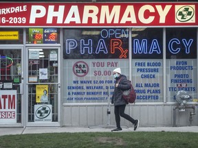 A pedestrian walks past a pharmacy in Parkdale, Toronto.