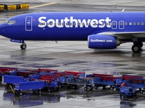 A Southwest Airlines jet passes unused luggage carts as it arrives, Dec. 28, 2022, at Sky Harbor International Airport in Phoenix. Congress is hearing today about the December meltdown at Southwest Airlines. A Southwest executive said in prepared testimony Thursday, Feb. 9, 2023 that the airline is taking steps to avoid a repeat of the breakdown that led to nearly 17,000 canceled flights over the December holidays.