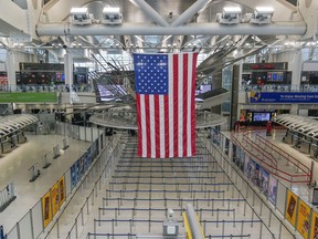 FILE -- An American flag hangs over a mostly empty Terminal 1 at John F. Kennedy International Airport in New York, Feb. 17, 2023. Work crews have fixed a power outage at the airport that forced some flights to be canceled or diverted, officials said Saturday, Feb. 18, 2023.