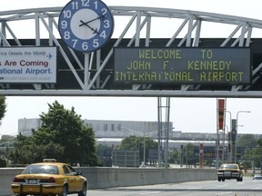 FILE - A clock at the entrance to JFK Airport in New York is pictured on Aug. 15, 2003. Officials are investigating a close call at the New York airport that happened Friday, Jan. 13, 2023, between a plane that was crossing a runway and another that was preparing for takeoff.