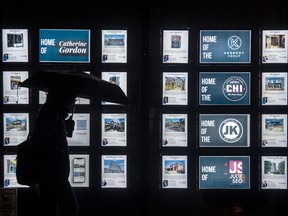 A pedestrian walks past real estate listings in Toronto.