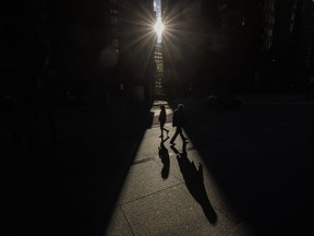 A new BMO report suggests excess household savings in Canada and the U.S. may help both countries avoid a severe economic downturn amid high interest rates. Pedestrians walk through a sliver of sunlight in the financial district in downtown Toronto on Wednesday July 6, 2022.