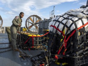 In this image released by the U.S. Navy, sailors assigned to Assault Craft Unit 4 prepare material recovered off the coast of Myrtle Beach, S.C., in the Atlantic Ocean from the shooting down of a Chinese high-altitude balloon, for transport to the FBI, at Joint Expeditionary Base Little Creek in Virginia Beach, Va., on Feb. 10, 2023. The federal government's lack of information about four aerial objects recently shot down over North America is helping to fuel conspiracy theories and conjecture on the internet.