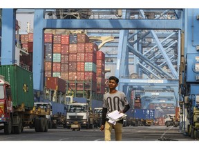 An employee works as he walks under gantry cranes at JNPT (Jawaharlal Nehru Port Terminal ) port in Navi Mumbai, India, on Saturday, Dec 16, 2017. Photographer: Dhiraj Singh/Bloomberg