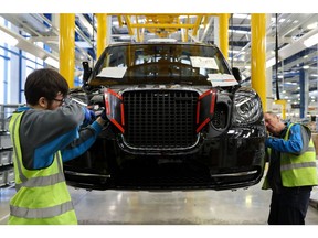 Employees adjust fittings on a TX electric black taxi, manufactured by the London EV Co., at the production plant in Coventry, U.K., on Monday, Feb. 5, 2018. The factory started producing the electric cabs in 2018, the date when all new taxis on London's streets need to be zero-emissions capable, with either pure electric or hybrid motors. Photographer: Simon Dawson/Bloomberg