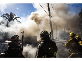 Firefighters work to extinguish a structure fire in the Montclair Hills neighborhood of Oakland, California, U.S., on Tuesday, Oct. 27, 2020. The preliminary cause of the fire was an overloaded generator, according to the Oakland Fire Department. PG&E Corp. cut power in the area to prevent live wires from falling into dry brush during the wind storms that have parts of the East Bay under a Red Flag Warning.