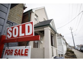 A "Sold" sign in front of a home in the York neighborhood of Toronto, Ontario, Canada, on Thursday, March 11, 2021. The buying, selling and building of homes in Canada takes up a larger share of the economy than it does in any other developed country in the world, according to the Bank of International Settlements, and also soaks up a larger share of investment capital than in any of Canada's peers.