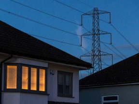 A light on at a residential home near an electricity transmission tower in Upminster, UK, on Monday, July 4, 2022. The UK is set to water down one of its key climate change policies as it battles soaring energy prices that have contributed to a cost-of-living crisis for millions of consumers.