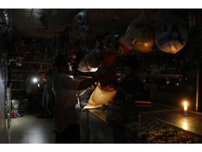A worker uses a candle to continue business during the power outage in Dhaka in Oct. 2022.