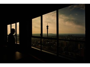 A visitor looks out towards the Telkom Tower and city skyline from the Ponte City Apartments building in the Berea district of Johannesburg, South Africa, on Thursday, Dec. 22, 2022. Johannesburg, South Africa's economic hub and its richest city, is seeking electricity supply from private generators to reduce the amount of scheduled power outages. Photographer: Waldo Swiegers/Bloomberg