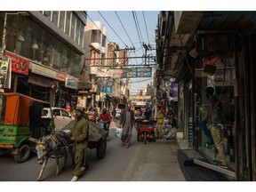 People walk under power lines in a commercial area in Lahore, Pakistan, on Monday, Jan. 23, 2023. Millions of people across Pakistans major cities were plunged into a blackout prompted by a power grid failure, dealing another blow to the nation already reeling from surging energy costs.