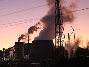 GELSENKIRCHEN, GERMANY - FEBRUARY 07: Water vapor rises from cooling towers of the coal-fired Scholven power station at sunset as a wind turbine spins nearby on February 07, 2023 in Gelsenkirchen, Germany. German Chancellor Olaf Scholz recently announced that his government, in cooperation with Germany's 16 states, will seek a rapid expansion of wind power capacity. Germany currently operates approximately 28,000 onshore wind turbines with an output of 58 gigawatts. Scholz's goal is 115 gigawatts generated from wind by 2030. Germany is also planning to end coal-fired power production by 2038 and in some states, including North Rhine-Westphalia, already by 2030.