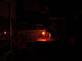 A customer waits for food by candlelight in a restaurant during a loadshedding power outage period, in Johannesburg, South Africa, on Monday, Feb. 13, 2023. Eskom Holdings SOC Ltd., which supplies most of South Africa's power from coal-fired plants, has been implementing rolling blackouts since 2008 because it can't meet demand.