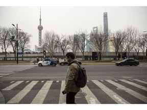 A pedestrian crosses a street near the Bund across from buildings in Pudong's Lujiazui financial district in Shanghai, China, on Tuesday, Feb. 28, 2023. After three years of turbulence under the Covid pandemic, China's leaders are expected to lay out economic goals to get growth back on track, restore confidence and avoid a build-up of financial risks. Photographer: Qilai Shen/Bloomberg