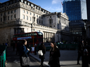 People walk outside the Bank of England in the City of London financial district in London.