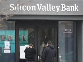 People look at signs posted outside of an entrance to Silicon Valley Bank in Santa Clara, Calif., Friday, March 10, 2023. The Federal Deposit Insurance Corporation is seizing the assets of Silicon Valley Bank, marking the largest bank failure since Washington Mutual during the height of the 2008 financial crisis. The FDIC ordered the closure of Silicon Valley Bank and immediately took position of all deposits at the bank Friday.