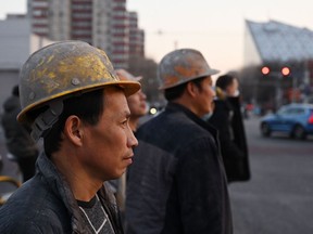 Construction workers wait to cross a road in Beijing on March 2, 2023.