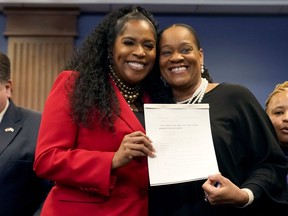 Illinois House Speaker pro-tem Jehan Gordon Booth, left, and Illinois Senate Majority Leader Kimberly Lightford pose with the Paid Leave For All Workers Act after Gov. J.B. Pritzker signed it into law Monday, March 13, 2023, in Chicago.