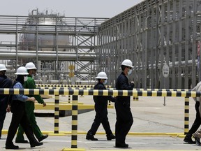 FILE - Saudi Aramco engineers escort reporters on a tour of the Hawiyah Natural Gas Liquids Recovery Plant, which is designed to process 4.0 billion standard cubic feet per day of sweet gas, a natural gas that does not contain significant amounts of hydrogen sulfide, in Hawiyah, in the Eastern Province of Saudi Arabia, on June 28, 2021. Saudi Arabia's state-owned oil giant Aramco will invest billions of dollars in China's downstream petrochemicals industry, including the construction of a new refinery, the company said in deals announced Sunday and Monday.