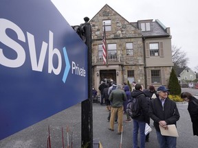 Customers and bystanders form a line outside a Silicon Valley Bank branch location, Monday, March 13, 2023, in Wellesley, Mass.