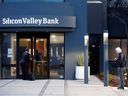 A bank employee waits to be let in as a customer lines up outside of the Silicon Valley Bank headquarters in Santa Clara, California.