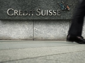 A pedestrian walks past a logo of Credit Suisse outside its office building in Hong Kong, China.