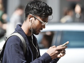 A man walks across Dundas Street at Yonge Street in Toronto while using his cell phone.