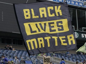 FILE - Seattle Sounders supporters fly a Black Lives Matter flag before an MLS soccer match against Atlanta United, May 23, 2021, in Seattle. On Wednesday, March 29, 2023, German sportswear company Adidas withdrew its opposition to a Black Lives Matter application with the U.S. Trademark Office two days after its filing. On Monday, March 27, Adidas submitted a notice of opposition with the office, saying in the filing that it took issue with Black Lives Matter Global Network Foundation's application to trademark the use of three parallel yellow stripes on various items such as clothing and bags.