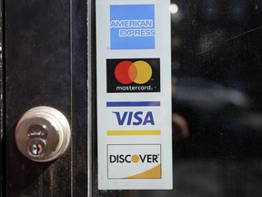 File - Credit card logos are displayed on a business's door, Monday, July 5, 2021, in Cambridge, Mass. As the Federal Reserve considers whether to raise interest rates again, credit card debt is already at record highs, and more people are carrying debt month to month.