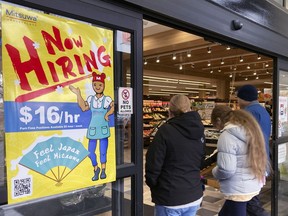 FILE - A hiring sign is displayed at a grocery store in Arlington Heights, Ill., Friday, Jan. 13, 2023. A strong job market has helped fuel the inflation pressures that have led the Federal Reserve to keep raising interest rates.