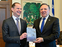 Quebec Finance Minister Eric Girard and Premier Francois Legault hold a copy of the province's latest budget, released on March 21. 