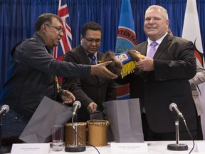 Ontario Premier Doug Ford, right, Chief Cornelius Wabasse, Webequie First Nation, left, and Chief Bruce Achneepineskum, Marten Falls First Nation, centre, give each other gifts after their signed agreement regarding a planned Ring of Fire road.