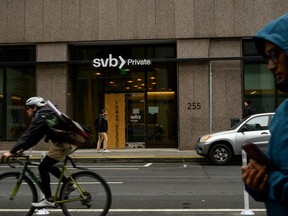Pedestrians and a cyclist pass by the Silicon Valley Bank branch office in downtown San Francisco, on March 13.