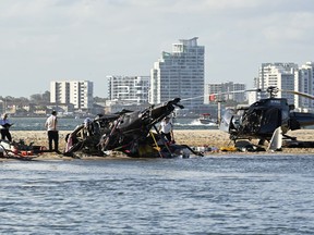 Investigators work at the scene of a dual helicopter collision near Seaworld, on Australia's Gold Coast, Jan. 2, 2023. A helicopter pilot told investigators he didn't hear a pilot on the ground announce he was taking off before the fatal collision of their aircraft at an Australian theme park, according to the preliminary report released Tuesday, March 7, 2023.